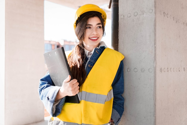 Engineer woman in helmet and vest with a clipboard in hands