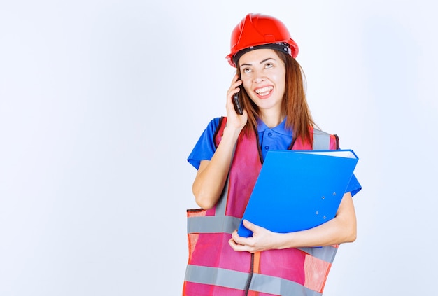 Engineer woman in red helmet talking to the phone. 