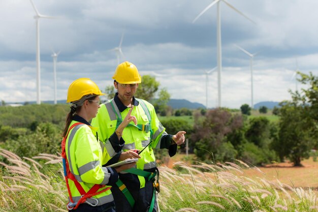 Engineer and worker discussing the project on the background of wind turbines