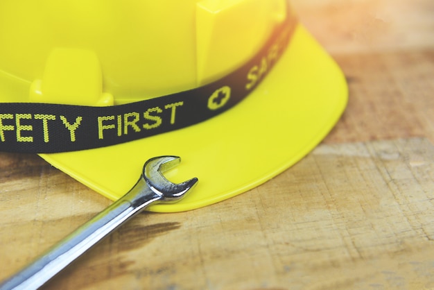 Фото Инженер рабочий шлем и гаечный ключ на деревянные безопасность прежде всего желтый жесткий защитный шлем шлем