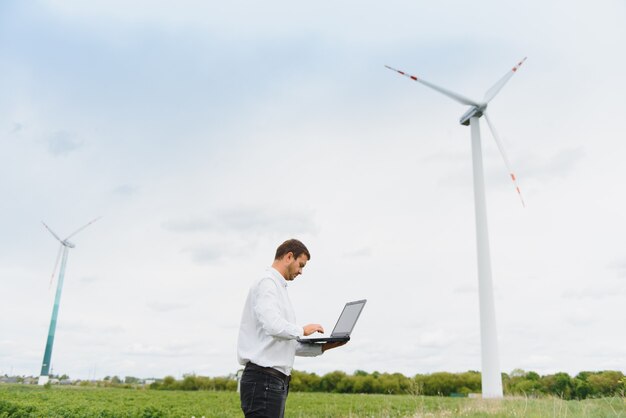 Engineer worker with laptop or computer at wind turbine power station construction site,copy space.