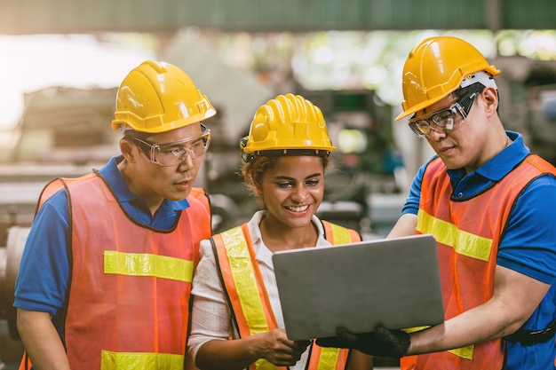 Engineer worker woman with male team working together in factory looking at Laptop computer happy smile