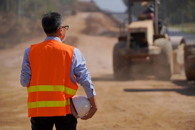 道路建設に取り組んでいるエンジニアまたは労働者は、掘削機とローラーコンパックで作業します