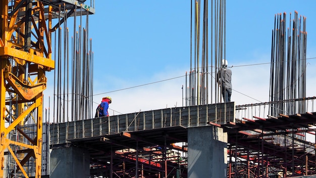 Engineer and workers on high building construction site and steel and cement texture and blue sky.