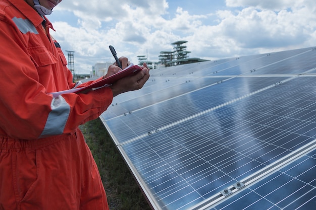 太陽光発電所の電気機器の点検とメンテナンスに取り組んでいるエンジニア;太陽光発電所での日常操作でソーラーパネルを点検するエンジニア