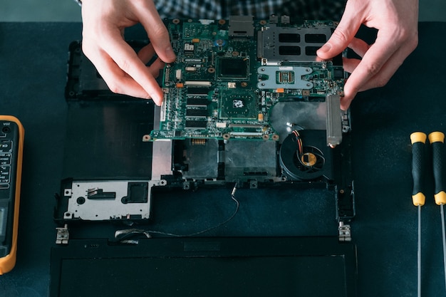 Photo engineer working on disassembled laptop