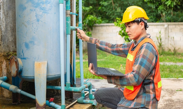 Engineer working in drinking water factory using a laptop computer to check water management system