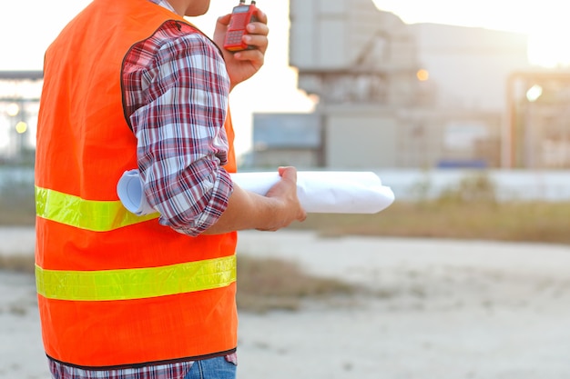 Engineer working on outdoor with citizen band radio and plan on building site