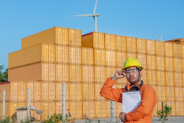 Engineer working at place for keep containerForeman wearing hardhat standing at the container yard and Check container integrity