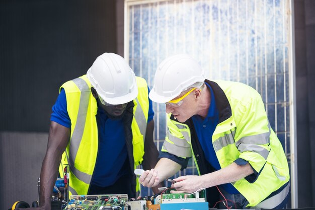 Engineer working repairing electric panel with solar panels background, Concept teamwork or training of renewable.