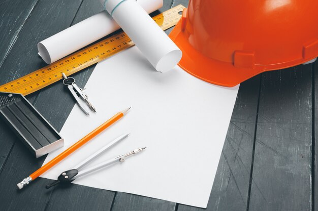 Engineer workplace with blueprints, compass, pencil and safety helmet