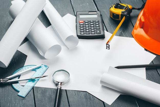 Engineer workplace with blueprints, compass, pencil and safety helmet