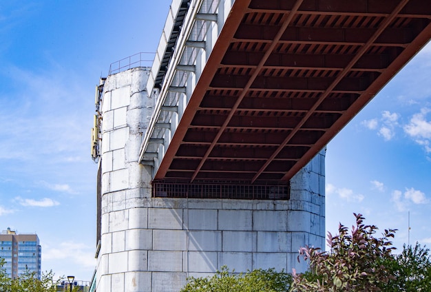 Engineering design of the metro bridge with concrete supports bottom view Panorama of the city with sky and trees