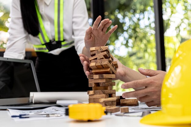 Engineers and architects are playing on wooden game condos on top of desks, comparing playing wooden games to standardized and beautiful building designs. Interior design ideas.