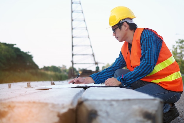 Engineers are reading the blueprint that is placed on piles in the construction area