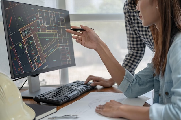 Photo engineers discuss a blueprint while checking information on a tablet computer in a office