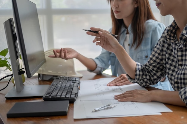 Photo engineers discuss a blueprint while checking information on a tablet computer in a office