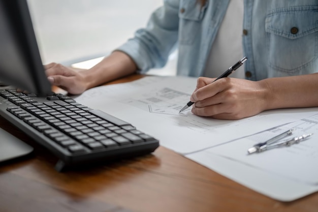 Photo engineers discuss a blueprint while checking information on a tablet computer in a office