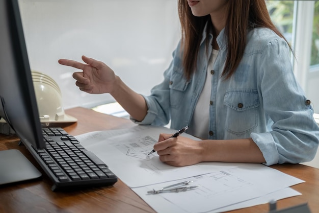 Photo engineers discuss a blueprint while checking information on a tablet computer in a office