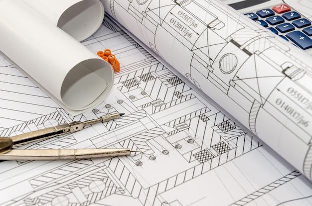 Engineers drawing with compass, calculator and rolls