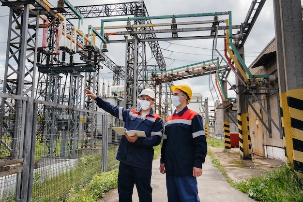 Engineers electrical substations conduct a survey of modern high-voltage equipment in the mask at the time of pandemia. Energy. Industry.