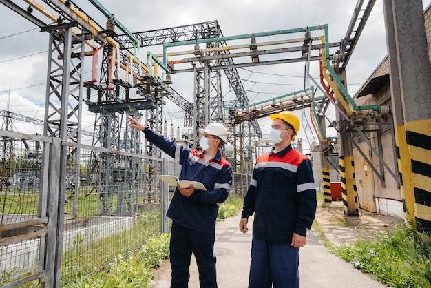 Engineers electrical substations conduct a survey of modern high-voltage equipment in the mask at the time of pandemia