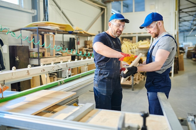 Engineers examining wooden plank at factory