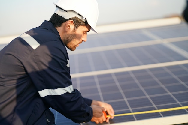 屋根に太陽光パネルを設置する技術者 太陽光発電パネルの列を歩く男性技術者