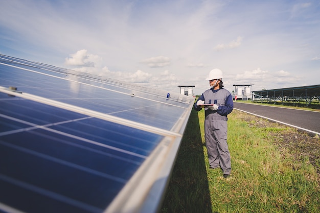 Photo engineers repairing solar panel at generating power of solar power plant ; technician in industry uniform on level of job description at industrial