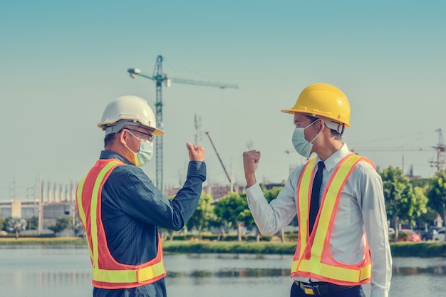 Engineers saluting each other by touching elbows,Two business people shake hand no touch outdoor on site construction
