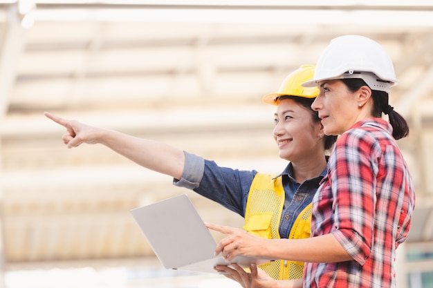 Engineers two woman working on plan building construction with laptop in city