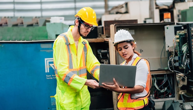 Engineers using laptop while standing in factory