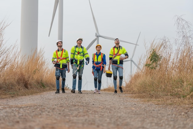 エンジニアの風車チームは、風力タービンのメンテナンス後に風力発電所で調査作業を歩きます