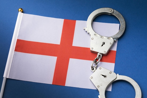 Foto inghilterra croce di st george red white flag e manette su sfondo blu, concetto di criminalità