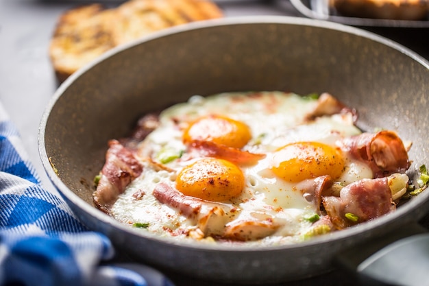 English breakfast fried bacon ham and eggs in ceramic pan.