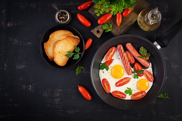 English breakfast - fried egg,  tomatoes, sausage,  and toasts. Top view, overhead