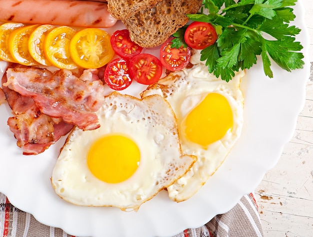 English breakfast - fried eggs, bacon, sausages and toasted rye bread