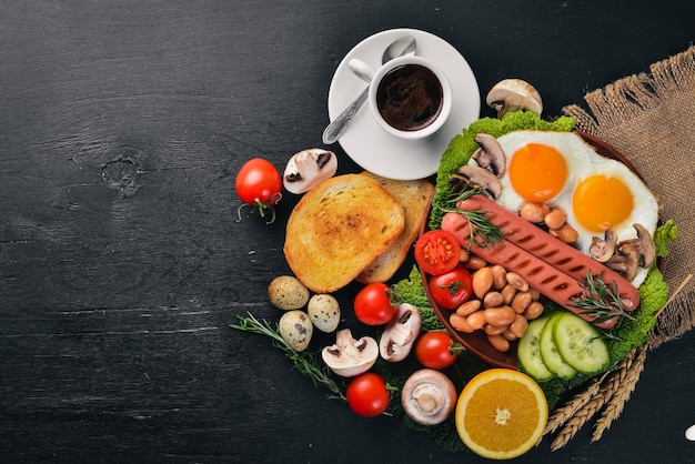 English breakfast Fried eggs sausages bacon beans toasts tomatoes coffee cup on stone table Top view with space for your text