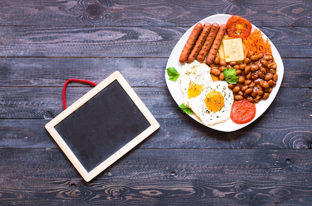 English breakfast. Fried eggs, sausages, beans, bread toasts, tomatoes, cheese,