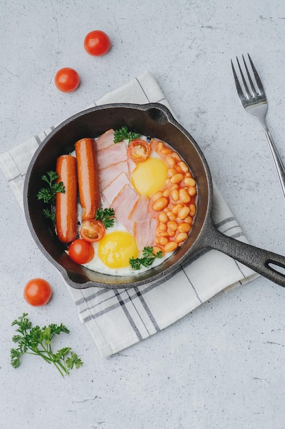 English breakfast on a frying pan Eggs sausages bacon tomatoes and beans