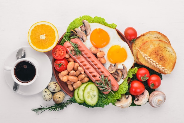 English breakfast tomatoes sausages beans mushrooms eggstoast and herbs top view On a white wooden background