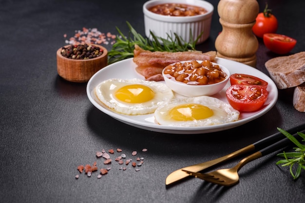 English breakfast with fried eggs bacon beans tomatoes spices and herbs