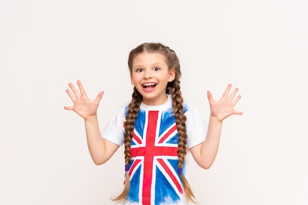 English language courses A little girl with a big smile with the flag of Great Britain on an isolated white background