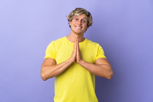 English man isolated purple background keeps palm together