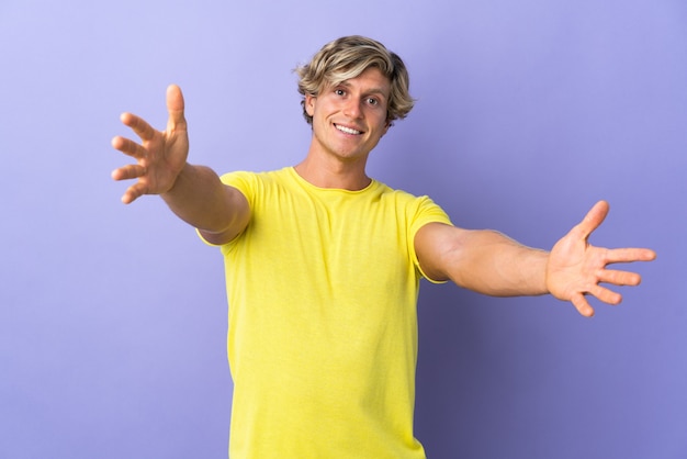 English man over isolated purple presenting and inviting to come with hand