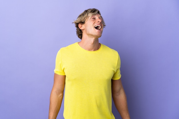 English man over isolated purple wall laughing