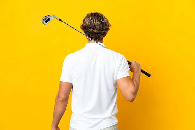 Photo english man over isolated white background playing golf and in back position