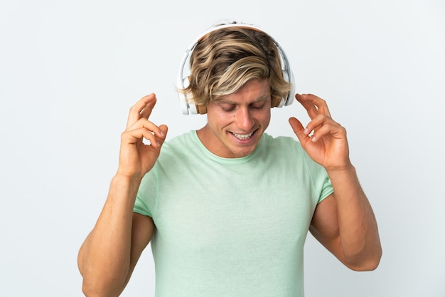 English man over isolated white wall listening music