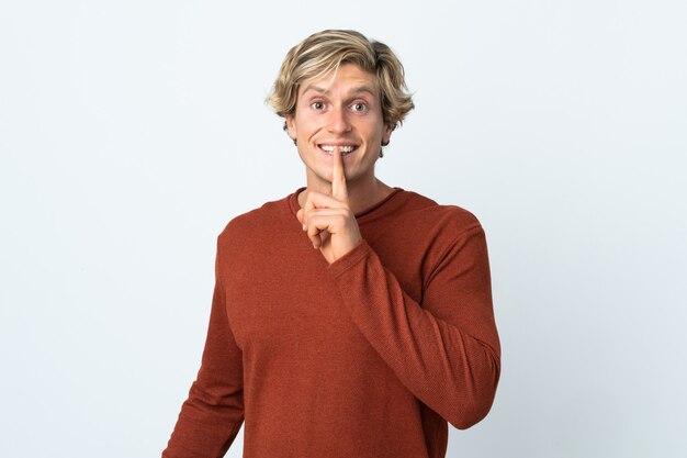 English man over isolated white wall showing a sign of silence gesture putting finger in mouth