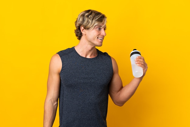 English man over isolated yellow background with sports water bottle